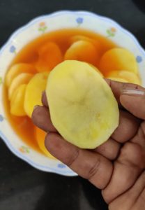 Sliced potatoes soaked in water with salt and red chili powder to make Aloo Pakora | Alu Bhajiya | Potato Pakoda