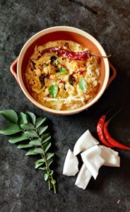 Coconut Chutney Recipe | Nariyal chutney served in brown bowl along with coconut pices, curry leaves and whole red chili 
