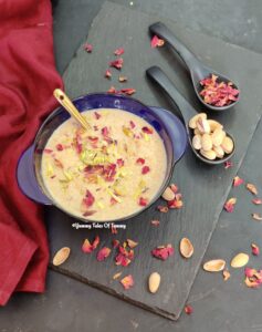 Chawal ki kheer served in blue bowl with pistachios and dried rose petals