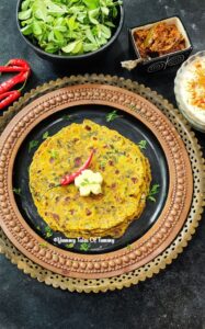 Methi Thepla Recipe | Gujarati Thepla | Methi na Thepla served on a metal plate with blob of butter, curd and pickle on side 