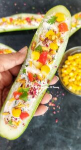 Low Carb Cucumber Boats | Cucumber boat Salad held in hand with boiled corn served in a bowl on side