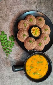 Instant Ragi Rava Idli | Ragi Idli served on black plate with sambar and coconut chutney 