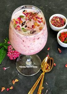 Rose falooda served in a glass with tutti fruity on the aide