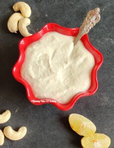 Vegan Cashew Cream Recipe | Cashew Cream served in red bowl with cashews and lemon slices on the side