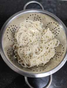 Cooked noodles placed in colander 