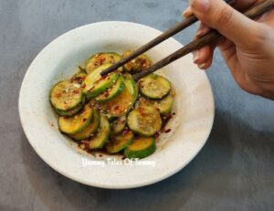 Vegan Asian cucumber salad served on white plate with chopsticks 