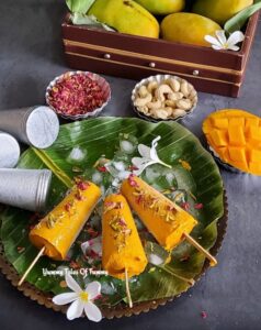 Mango Kulfi Recipe (no cream no refined sugar) garnished with rose petals and pistachios on the bed of ice cubes 