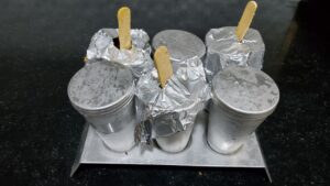 Aluminium kulfi molds filled with mango kulfi