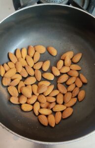 Whole almonds being roasted in a pan on stove top 