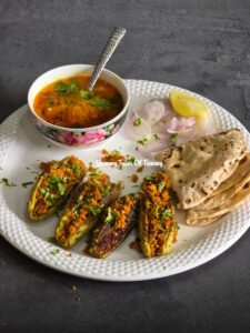 Bharwa Karela | Stuffed Bitter Gourd served with chapatis and dal in a white plate