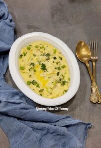 Garlic herb Mashed Potatoes served in white platter with spoon and fork on the side