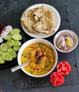Rajasthani Gatte ki Sabzi served with salad, chopped onions and chapatis