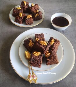 Eggless Chocolate Brownies Recipe served with walnuts and chocolate sauce on the side
