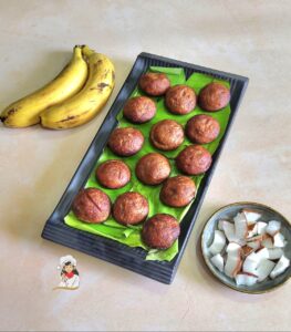 Banana Appam | Whole Wheat Banana Paniyaram served in a black platter with bananas and coconut on the side
