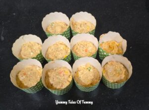 Muffin molds filled with Eggless Pizza Muffins Recipe (yeast free) batter upto half 